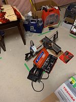 Photo of assorted tools showing Craftsman sabre saw, ratchet socket set, and bits in plastic containers on a concrete floor.