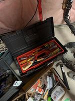 Box toolbox open showing inside compartments with screwdrivers, hammer, pliers and caulking gun plus other hand tools