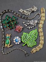Various signed Weiss rhinestone costume jewelry laid out on black fabric showing brooches, bracelets, earrings, and a necklace.