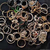 Overview of assorted rhinestone pave costume jewelry bracelets on black fabric background.
