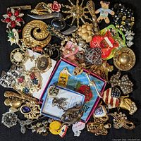 Photo showing a variety of brooches and pins of various themes, some new in packaging, including floral, sun-shaped, patriotic, and novelty designs.