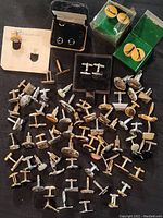 Full lot view of cufflinks with some in original boxes, varying styles and materials.