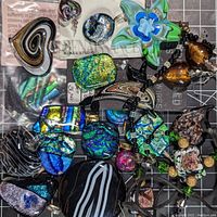 Various art glass pendants shown together including multiple dichroic glass types and some with layered color effects in multiple shapes and colors including hearts, abstract shapes, oval and circular pieces.