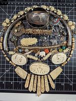 Top-down shot of the full jewelry collection laid out on a grid cutting mat to show size and detail.