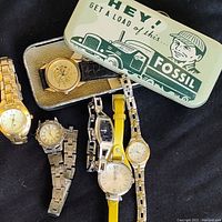 Photo showing all five Fossil ladies wristwatches arranged with the vintage Fossil watch box. Various strap types and dial styles visible.