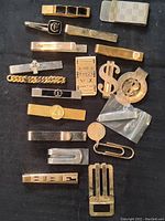 Top-down view of 18 assorted money clips of various designs and finishes.