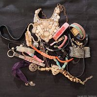 Full assortment of rhinestone and leather costume jewelry including necklaces and bracelets, laid out against black fabric background.
