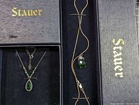Two Stauer branded jewelry boxes with sterling silver necklaces showcasing green Helenite stones.