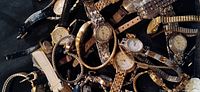 Multiple Timex ladies quartz wristwatches piled on a black surface showing different strap styles and watch face designs.