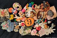Top view showing assortment of colorful, themed novelty brooches arranged on black fabric background