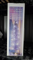 Photo of packaged box showing 14 inch glitter Christmas tree product with image and product information in multiple languages including English and German.