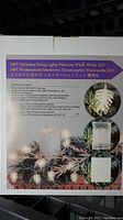 Box showing product details including that the string measures 16 feet and features warm white LED pinecone-shaped lights. Battery pack included.