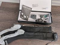 Box open with grey and black heated socks laid out along with power adapters and user guide inside the box