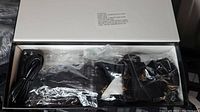 Photo of opened box containing black heated socks, charging cables, and battery packs wrapped in plastic.