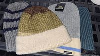 Photo of four men's knitted toques in various colors and patterns laid out on a surface.