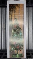 Photo shows the packaged box of the 14 inch glitter Christmas tree with LED lights showing product details on front.