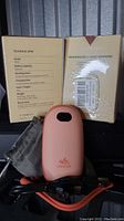Photo showing two Unigear rechargeable hand warmers coral color, USB cables, soft sleeves, and original packaging.