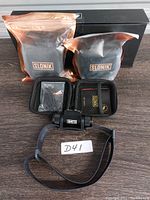 Photo showing the Slonik headlamp with adjustable strap, sealed battery pack, sealed accessory parts, and black box packaging with branding.