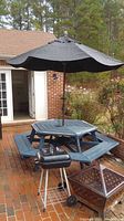 Image showing the hexagonal black painted wooden picnic table with six benches and black umbrella in outdoor patio setting.