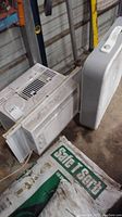 White Arctic King window air conditioner and white Aerospeed box fan together on the floor