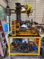 Full view of yellow Dayton milling machine mounted on rolling steel cart with tools on lower shelf