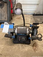 Front view of the delta dual wheel bench grinder with attached lamp and base. Shows grinding wheels and safety features.