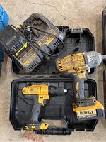 Photo showing DeWalt cordless impact drill, 1/2 inch drill, two chargers in black carrying case.