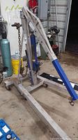 Full view of the Duralast engine lift showing blue and white steel frame with lifting chain and hydraulic pump.