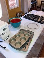 Mini refrigerator, mixing bowls with lids, muffin pans, and Lazy Susan on table