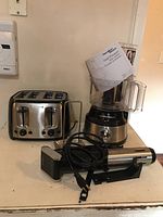 Photo showing Black & Decker toaster, Hamilton Beach food processor with manual, SilverCrest sous vide immersion circulator on a counter.