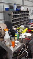 Workbench filled with various tools, cleaning sprays, and a bench organizer for small parts