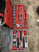 Red plastic case containing a large ratchet handle, 21 sockets of varying sizes, 2 extension bars, and a universal joint adapter.