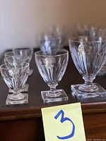 Close-up front angle showing small, medium, and large crystal goblets with cut glass design and square bases.