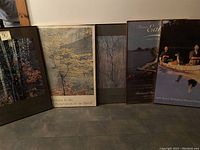 Five framed outdoor themed prints lined up on floor, visible title details and framing