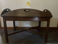 Photo of the antique butler table showing its full front view with curved backrest and carry handles.
