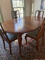 Photo of oval antique wood dining table with four matched chairs, showing cabriole legs and wood grain.