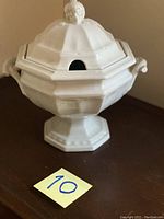 Front view of large white ceramic soup tureen with lid, showing hexagonal faceted design and pedestal base