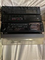 Black Denon stereo components stacked: amplifier, CD player, cassette deck with cassette tape