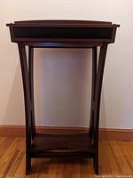 Front view of mahogany lectern showing top surface, curved legs, and lower inset shelf.