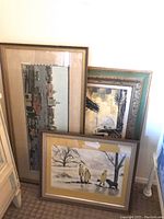 Three framed artworks displayed leaning against a wall, showing size and framing styles.