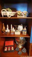 Full shelf showing all items including ceramic dish with faux grapes, flower trinket box, salt and pepper shakers, Jewish and Asian figurines