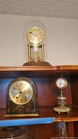 Overall shot showing three clocks: anniversary clock on top, hand painted mantel clock bottom left, marble and metal clock bottom right