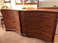 Front view of wooden dresser showing eight curved drawers and center cabinet with carved detailing.