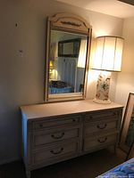 Photo of dresser with six drawers and matching mirror on top, showing entire furniture piece and room lighting.