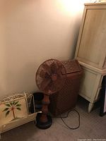 Image showing the metal floor fan next to the woven wastebasket and vintage magazine rack with palm tree design.