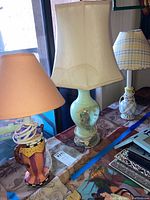 Three decorative lamps on table, showing different designs and lampshades