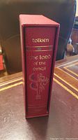 Spine of the red slipcase with gold embossed title 'The Lord of the Rings' and author name 'Tolkien' with decorative designs.
