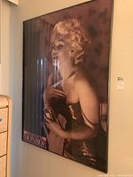 Full view of framed Marilyn Monroe poster showing the subject holding a perfume bottle in a glamorous pose.