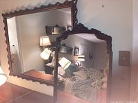 The two wood framed mirrors shown hanging in a bedroom, displaying size and style.