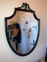 Large vintage wooden framed mirror with scratches, aged glass and decorative urn molding top.